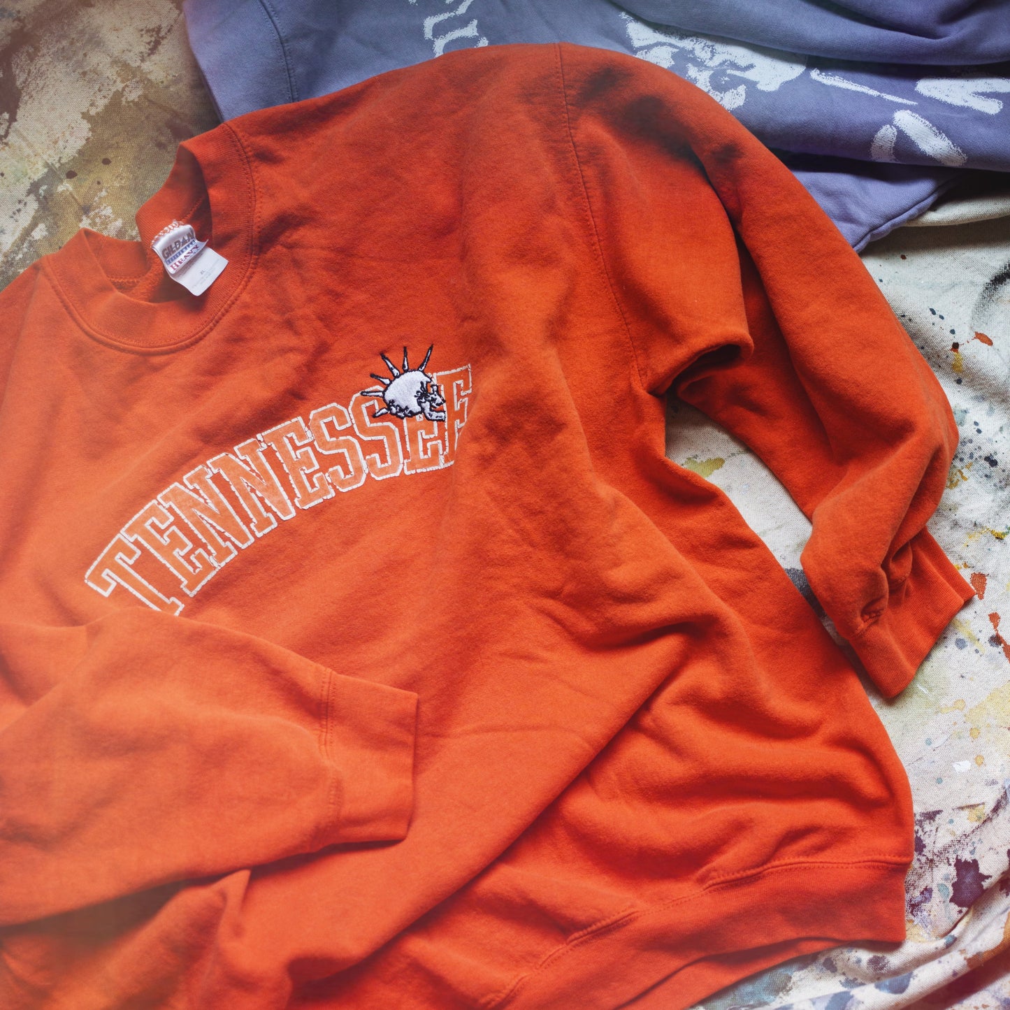 Orange sweatshirt with 'Tennessee' text and logo on a textured surface