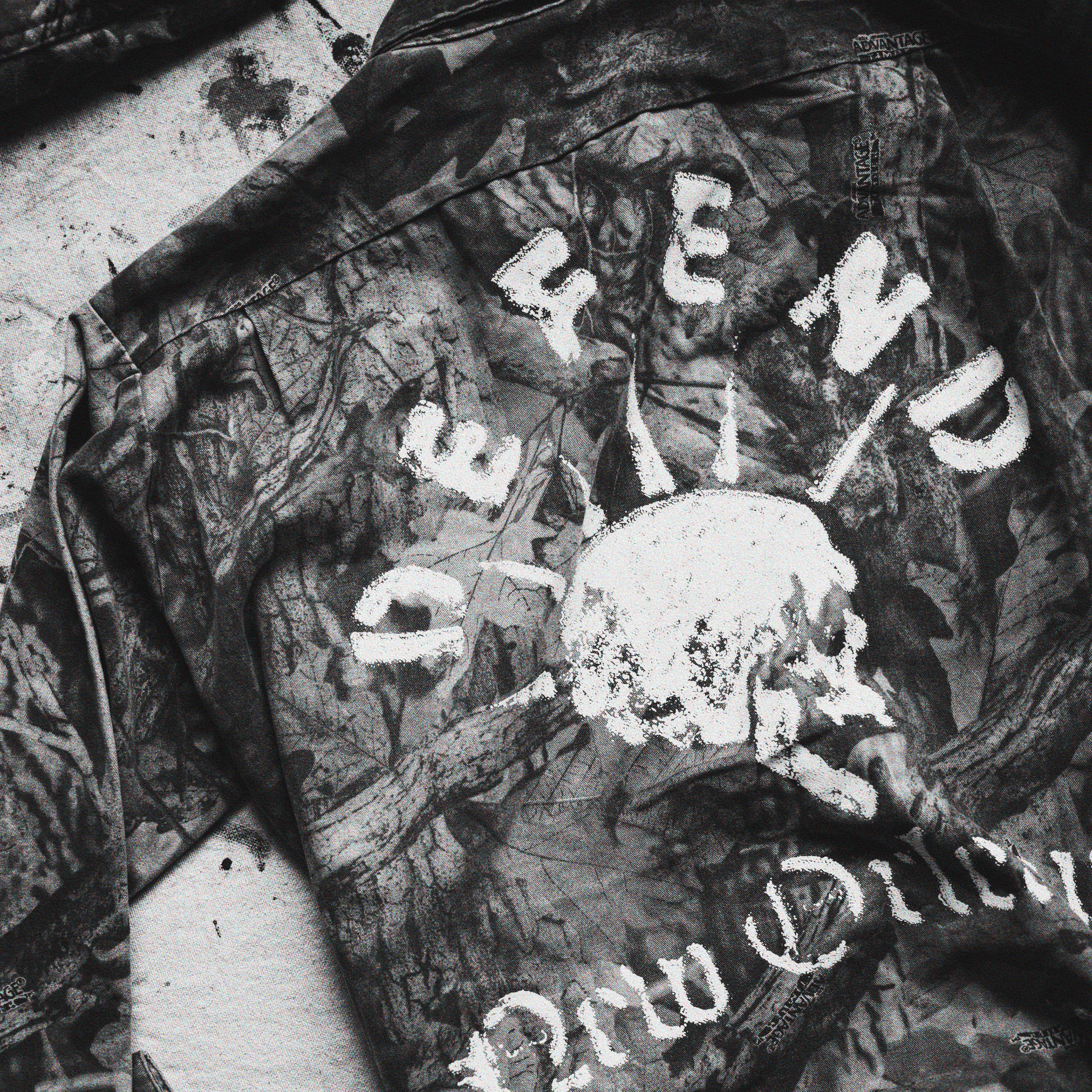 Camouflage jacket with 'Defend New Orleans' text and skull design on art studio drop cloth.