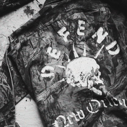 Camouflage jacket with 'Defend New Orleans' text and skull design on art studio drop cloth.