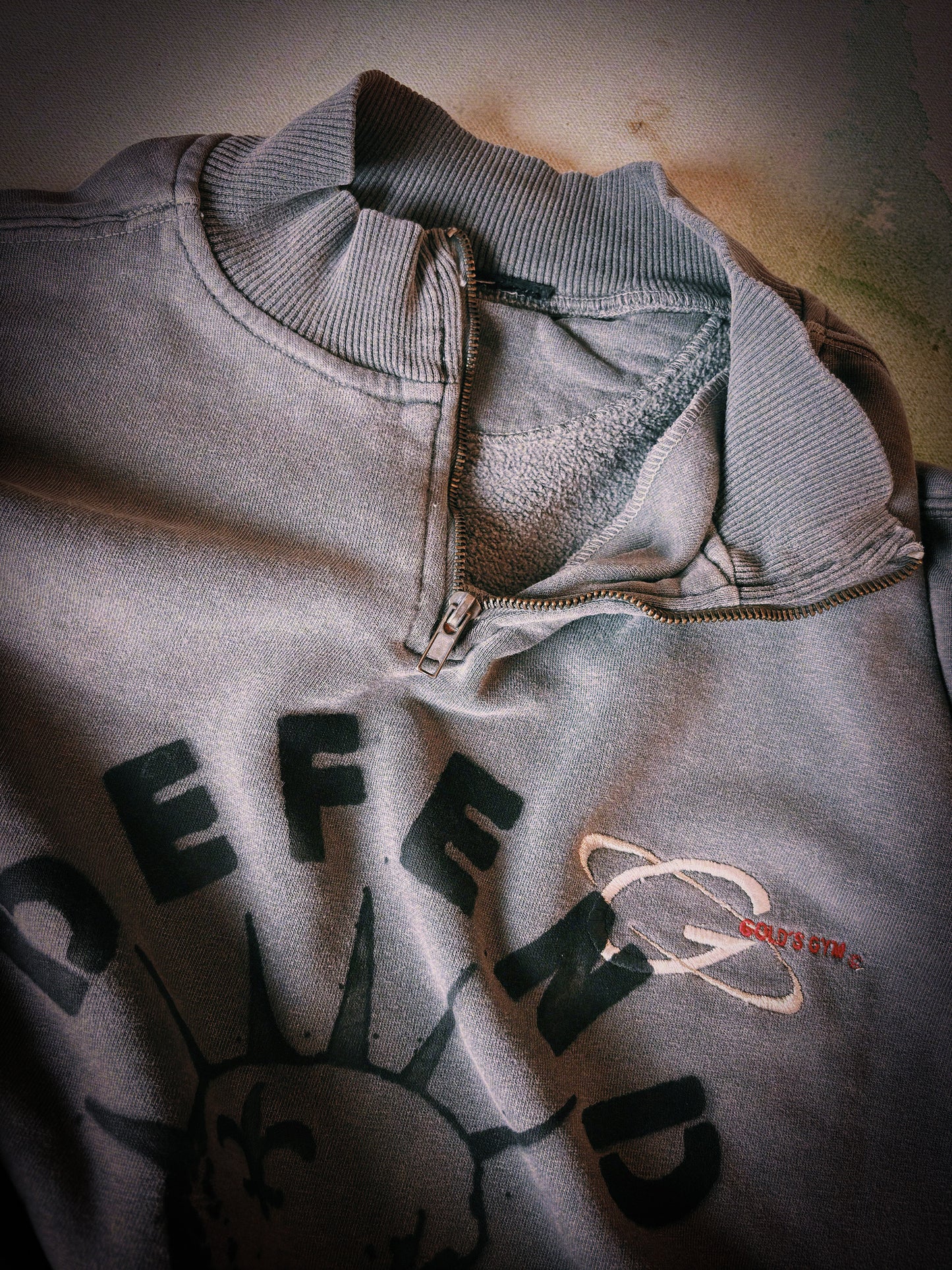 Gray sweatshirt with text and logo on a textured surface